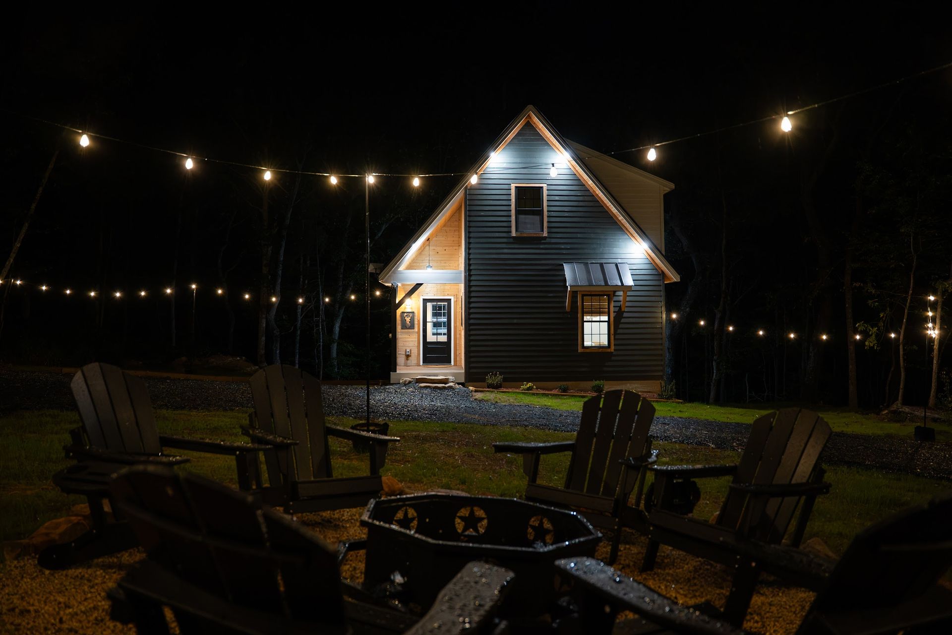 The Stag's fire pit and string lights at night, with the cabin glowing behind