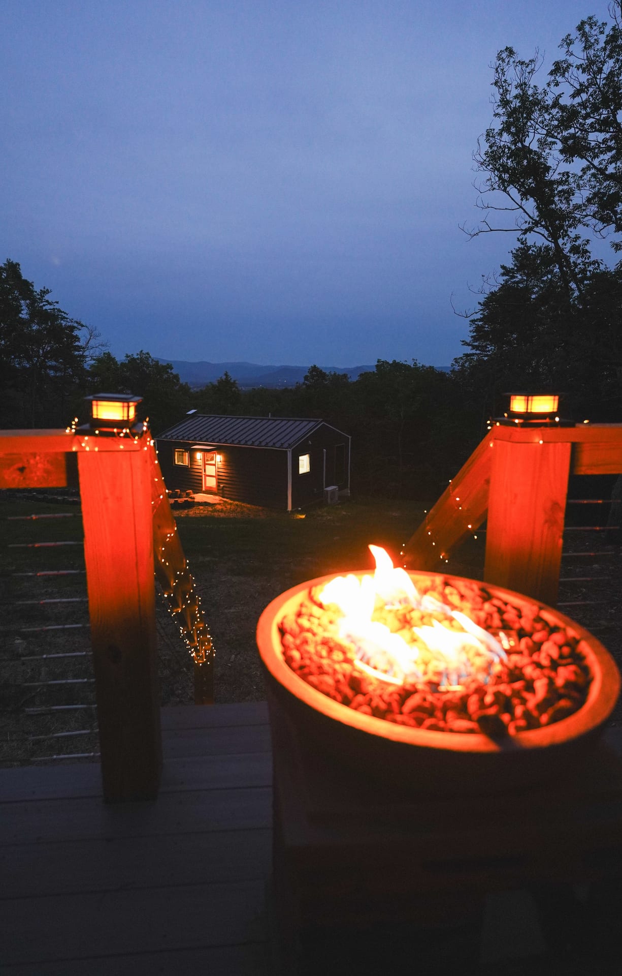 The Turtle lit at dusk behind its deck fire pit, with the ridge beyond